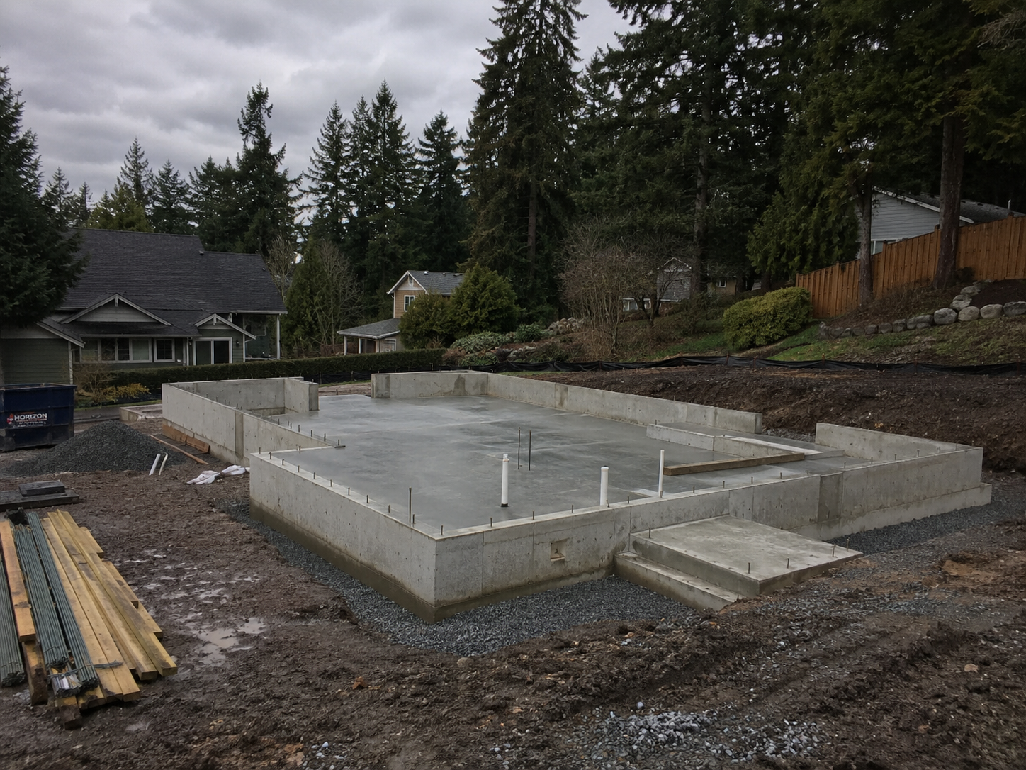 Poured concrete foundation with rebar, anchor bolts, and plumbing rough-in at a residential job site